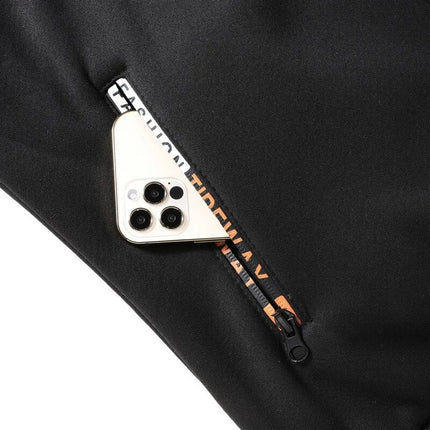 Smartphone half inserted into a zipped pocket of a black sherpa-lined men's hoodie, showing triple camera lens design.