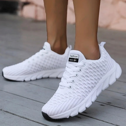 White women's lightweight breathable athletic sneakers on wooden floor, perfect for sports and casual wear.