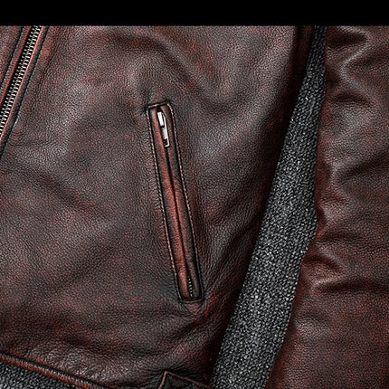 Close-up of a brown 100% cowhide leather jacket, showcasing the texture, zipper, and pocket detail of the sleeve and front.