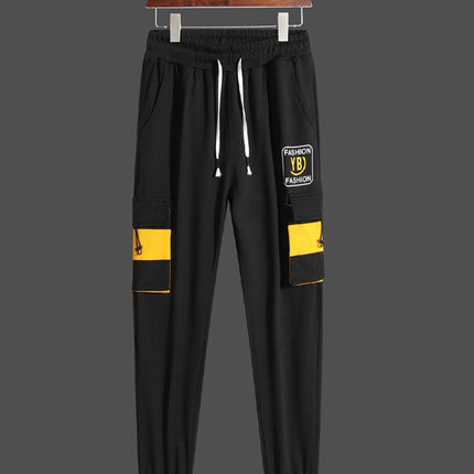Pantalón deportivo negro con cintura elástica y detalles gráficos amarillos, ideal para moda urbana masculina.