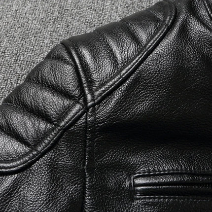 Detailed view of black 100% cowhide leather jacket with quilted shoulder and textured finish on gray background.