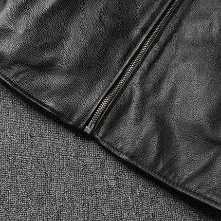 Close-up view of a 100% cowhide leather jacket, showcasing the high-quality texture and durable zipper details on a fabric background.