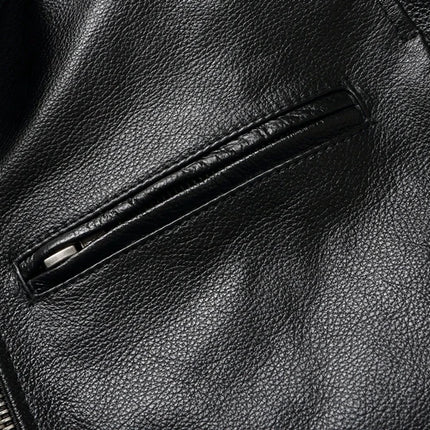 Close-up of a black cowhide leather jacket, showcasing the texture and quality of the 100% leather material with a front zipper pocket.