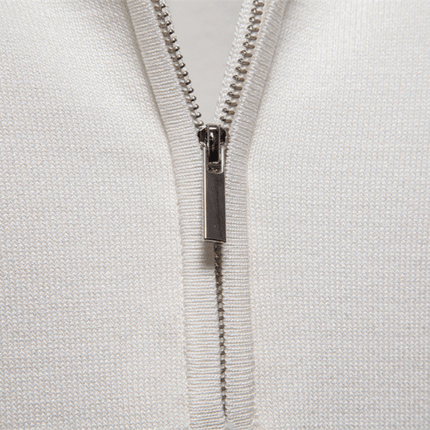 Cierre metálico en un tejido blanco con textura de canalé, enfoque en la cremallera para detalles de diseño elegante y moderno.