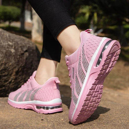 Mujer con zapatillas deportivas rosas transpirables con suela antiimpacto, mostrando diseño ergonómico en un entorno al aire libre.