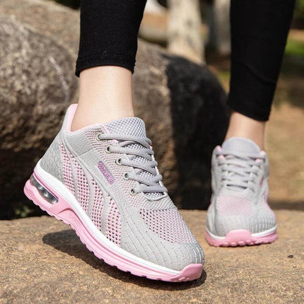 Persona usando zapatillas deportivas transpirables rosas y grises con suela antiimpacto, ideales para comodidad y soporte diario.