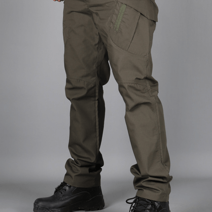 Hombre con pantalones cargo tácticos verdes, mostrando múltiples bolsillos y botas negras, ideal para uso urbano y resistente.