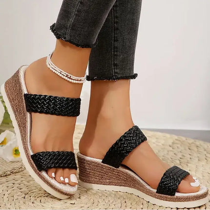 Woman wearing Easy Step wedge sandals, open-toe black braided straps, paired with skinny jeans, perfect for stylish summer comfort.