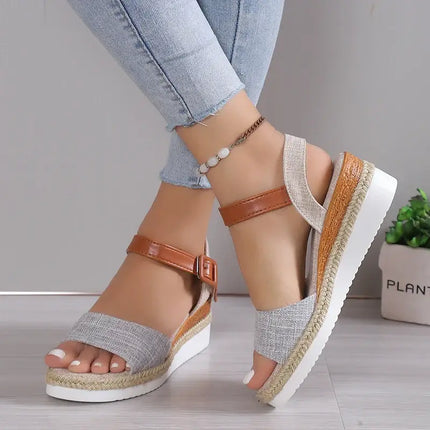 Woman wearing elegant wedge sandals with modern design, featuring soft grey straps and brown anklet, ideal for stylish summer outings.
