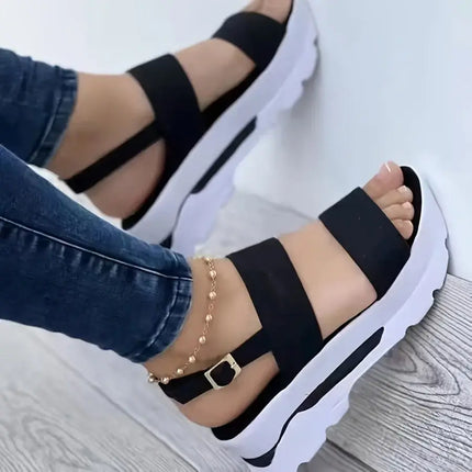 Woman wearing Sandalia Hebilla Zen with black straps and white wedge, showcasing adjustable buckle and open toe design.