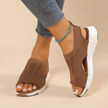 Woman wearing Sandalia Verano Fit with open toe and adjustable back strap for summer comfort, shown in brown with mid-height wedge heel.