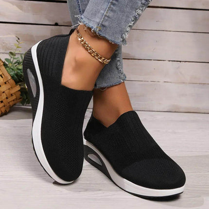 Comfortable black slip-on shoes with cushioned soles, perfect for all-day wear. Styled with casual jeans and an anklet.