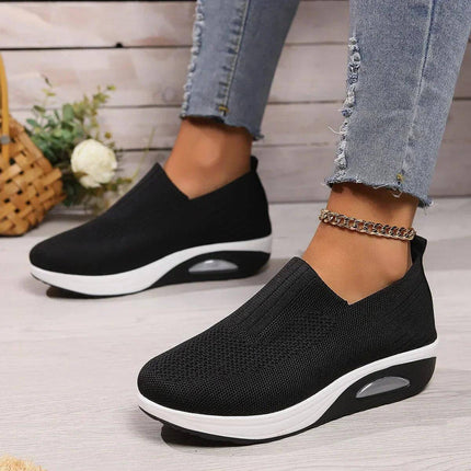 Zapatillas Confortplus negras, cómodas y elegantes, con suela blanca antiderrapante y diseño moderno para máximo confort y estilo diario.