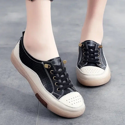 Woman wearing black and white genuine leather sneakers with perforated design and flexible sole for comfort.