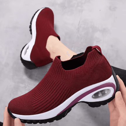 Mujer usando Zapatillas Hina en color burdeos, diseño ergonómico y suela antiimpacto para soporte y confort óptimo.
