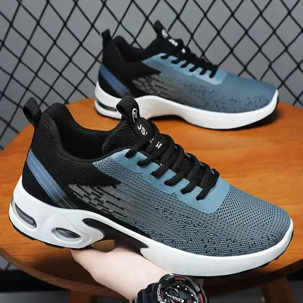 Zapatillas deportivas hombre de malla grises y negras, livianas y modernas sobre una mesa de madera, fondo con diseño geométrico.