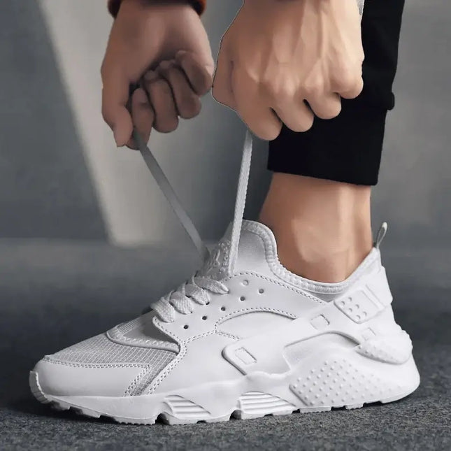 Hombre ajustando zapatillas deportivas blancas Street Air, ligeras y versátiles, ideales para uso diario, vista lateral.