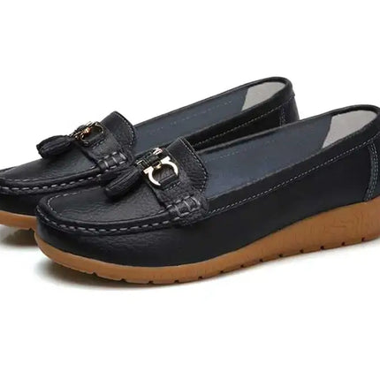 Zapatillas Mujer tipo mocasín negras con acabado tipo cuero y detalle metálico, diseño plano y flexible ideal para elegancia diaria.