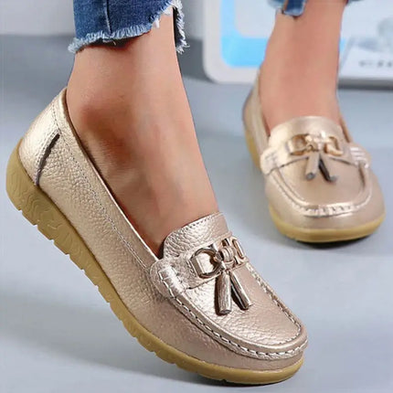 Elegantes zapatillas mocasín doradas para mujer con detalle metálico, diseño plano, ideales para comodidad y estilo diario.
