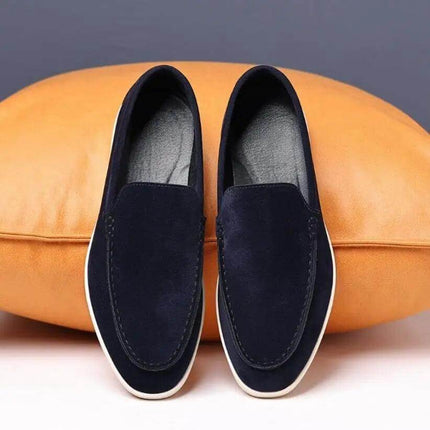 Zapatos casuales hombre sin cordones, azul oscuro, sobre cojín marrón, perfectos para estilo relajado y confort.