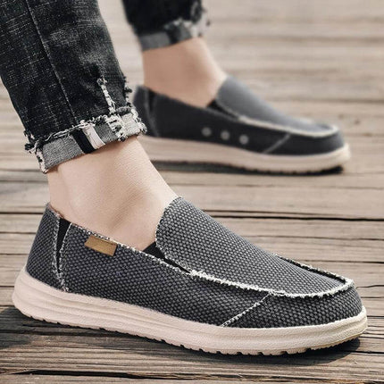 Hombre usando zapatos casuales de lona transpirables en gris, ideales para comodidad diaria y estilo relajado.